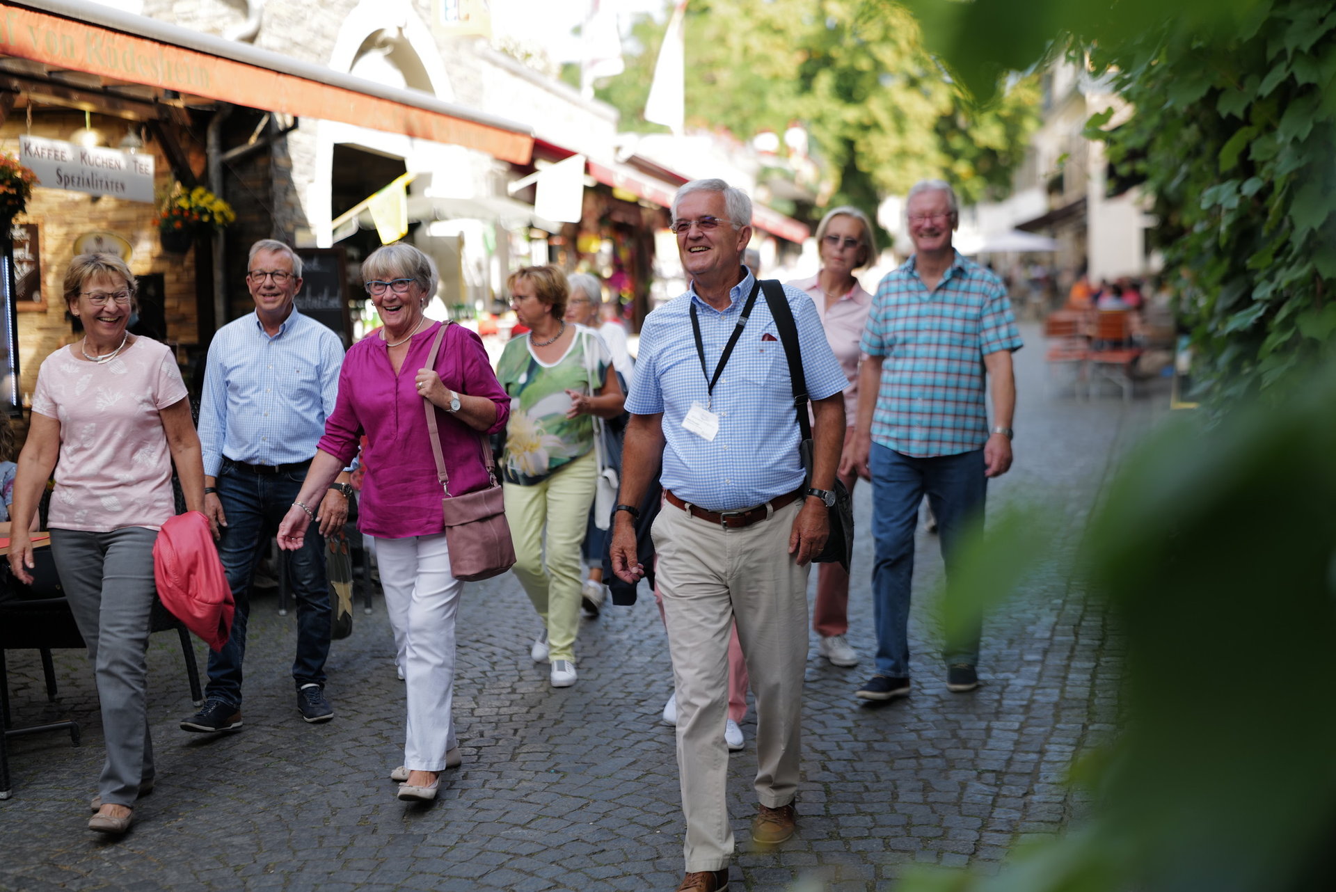 Eine Gruppe mit vielen Personen geht durch die engen Straßen von Rüdesheim. Im Vordergrund geht der Stadtführer erkennbar an einem Ausweis um den Hals.