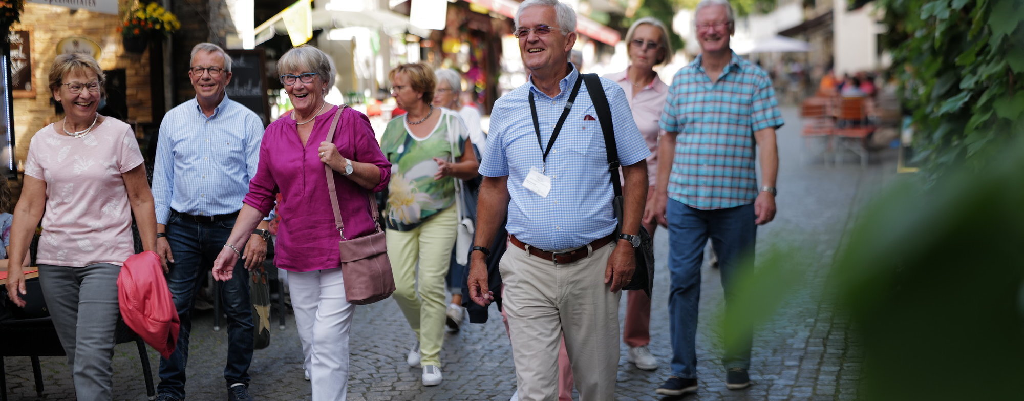Eine Gruppe mit vielen Personen geht durch die engen Straßen von Rüdesheim. Im Vordergrund geht der Stadtführer erkennbar an einem Ausweis um den Hals.