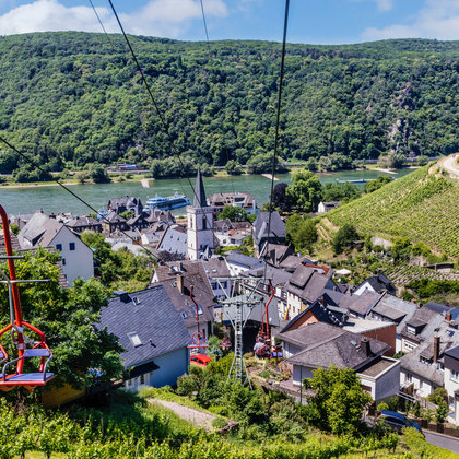 Die roten Sitze der Sesselliftbahn Assmannshausen schweben über Assmannshausen mit einem atemberaubenden Ausblick auf die Naturlandschaft und den Rhein.