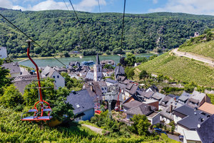 Die roten Sitze der Sesselliftbahn Assmannshausen schweben über Assmannshausen mit einem atemberaubenden Ausblick auf die Naturlandschaft und den Rhein.